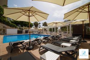 贝纳尔马德纳七村公寓的游泳池旁设有躺椅和遮阳伞的游泳池