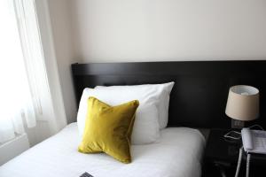 伦敦布卢姆斯伯里皇宫酒店的一张带黄色枕头和白色枕头的床