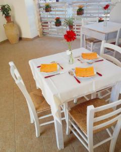 赛拉诺B&B Masseria Donna Carlotta的一张白色桌子,上面有红色的餐巾和红色的鲜花