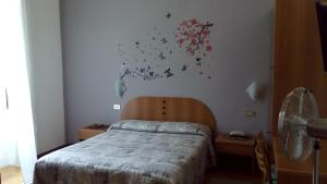 米兰Hotel Tirreno的卧室配有一张床,墙上挂有绘画作品
