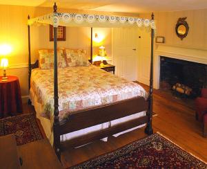 CamptonColonel Spencer Inn的一间卧室设有一张天蓬床和一个壁炉