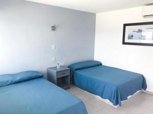 马萨特兰Mona Inn的配有蓝色床单的客房内的两张床