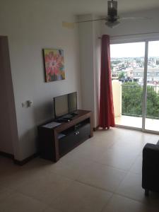 拉罗马纳玛吉之家公寓的客厅设有一张桌子和一扇窗户,配有电视。