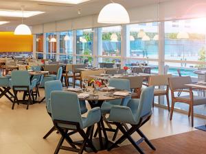 里约热内卢诺富特里约热内卢奥林匹克公园酒店的用餐室设有桌椅和窗户。