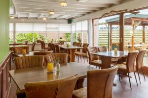 温特斯韦克Hotel Restaurant Mondriaan的餐厅设有木桌、椅子和窗户。