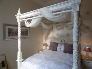 达农Douglas Park Guest House的卧室配有带窗帘的白色天蓬床