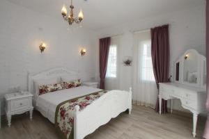 切什梅Alya Mou Butik Hotel的白色卧室配有白色的床和书桌