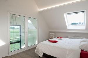 佐内贝克gastenverblijf 't Baertshof的卧室配有白色的床和2扇窗户。