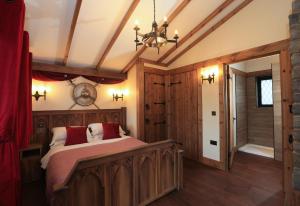 沃里克Warwick Castle Hotel & Knight's Village的一间卧室配有一张带红色枕头的大型木制床。