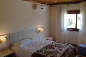 格拉玛多Residencial Aconchego do Lago的一间卧室设有一张大床和一个窗户。