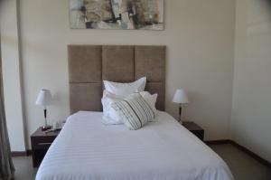 Kitwe帕莫餐厅酒店的一间卧室配有一张带两盏灯的大型白色床。