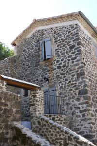 普里瓦Domaine de Chabanet的一座石头建筑,设有两扇窗户和阳台