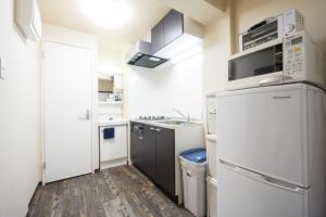 东京东京戈恩公寓式酒店的小厨房配有白色家电,铺有木地板