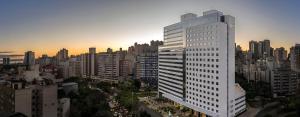 阿雷格里港Intercity Porto Alegre Cidade Baixa的日落时分在城市里高大的白色建筑