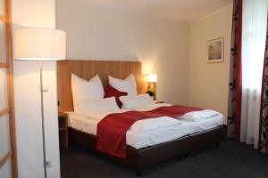 格拉斯布伦大使酒店的酒店客房,配有一张带红色毯子的床