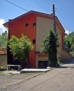 贝尔科维察Hotel Restaurant Vodenitsata的一座红色和白色的建筑,前面有长凳