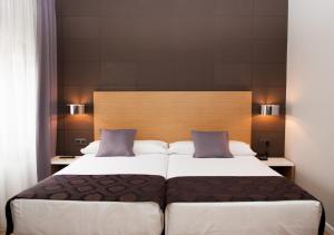 圣地亚哥－德孔波斯特拉环球酒店的一间卧室配有一张大床和木制床头板