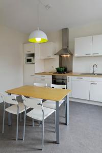 Herve乌埃布弗勒公寓的厨房配有木桌和白色橱柜。