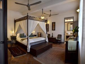 琅勃拉邦Satri House Hotel的一间卧室配有一张天蓬床和一张书桌