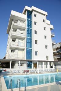 切塞纳蒂科Hotel Al Ragno的一座白色的大建筑,前面设有一个游泳池