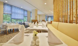 阿尔贝纳Maritim Hotel Paradise Blue的餐厅设有白色的桌椅和窗户。