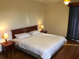 士姑来兰斯度假租赁公寓的一间卧室配有一张大床、两张桌子和两盏灯。