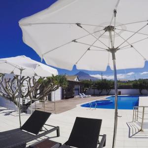 马达莱纳拜亚达巴卡酒店的一个带两把椅子和一把遮阳伞的庭院和一个游泳池