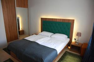 克塞洛Portré Apartman的一间卧室配有一张大床和绿色床头板