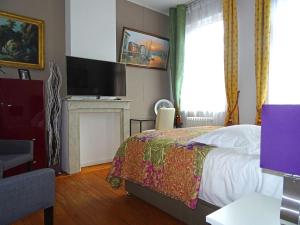 朗斯Chambres et Table d'hôtes La Belle Lensoise的一间卧室配有一张床、一台电视和一个壁炉