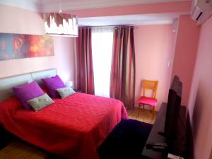 阿利坎特Explanada Beach Deluxe Flat的一间卧室配有红色的床、紫色枕头和窗户