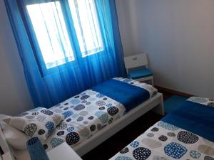 塞图巴尔Apartamento Sado的一间卧室设有两张床,窗户配有蓝色窗帘