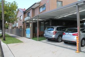 悉尼史卓菲行政住宿酒店的两辆汽车停在大楼前的停车场