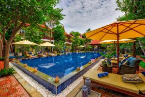 暹粒玛尼村套房酒店的度假村的游泳池,配有椅子和遮阳伞