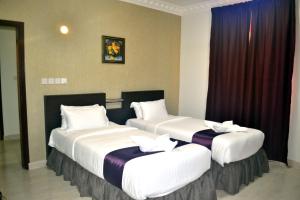 塞拉莱Gateway Salalah Apartments的两张床铺,位于带窗帘的酒店客房内