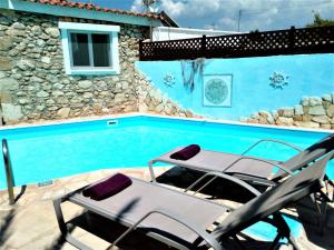 Peristerona佩瑞斯隆纳玫瑰园别墅酒店的一座房子旁的游泳池,配有两把躺椅