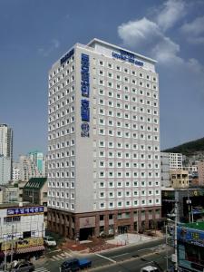 釜山釜山西面托优克酒店的一座白色的大建筑,上面有蓝色的标志