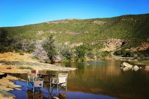 WaterfordKoedoeskop Private Mountain Reserve的两把椅子坐在河岸边