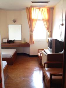 曼谷堃城大厦的一间卧室设有一张床、一台电视和一个窗口。