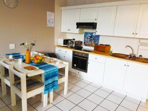 马盖特Dumela Margate Flat No 3的厨房配有白色橱柜和一张带食物的桌子。