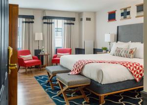 波特兰波特兰港大酒店 的一间卧室配有一张大床和红色椅子