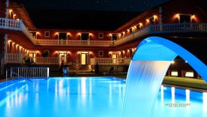 什图罗沃Artemis Resort Wellness Hotel的夜间在房子前面的游泳池