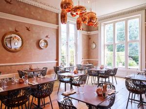 切尔滕纳姆Cotswold Grange的一间设有桌椅的餐厅,位于带窗户的房间内