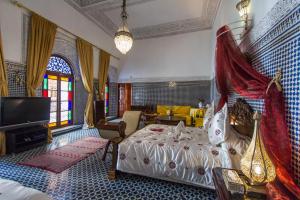 非斯Riad Damia Suite &Spa的一间卧室配有一张床和一台电视。