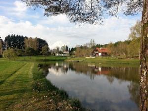 AugignacLieux-au-lac的公园内的一个池塘,有房子在后面