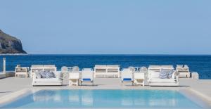 卡拉沃斯塔西翁波尔图精品酒店的一组椅子和一个毗邻大海的游泳池