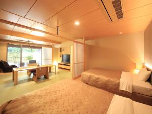 下田下田中央日式旅馆的一间卧室配有一张床和一张书桌及电视