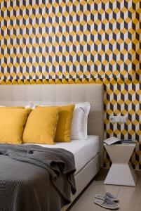 波托什缪斯公寓的一间卧室配有一张带黄色枕头的床和图案墙壁