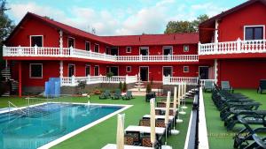 什图罗沃Artemis Resort Wellness Hotel的一座红色的建筑,前面设有一个游泳池