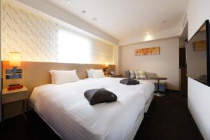福冈HOTEL FORZA HAKATA-GUCHI的酒店客房配有一张带两个枕头的大型白色床。