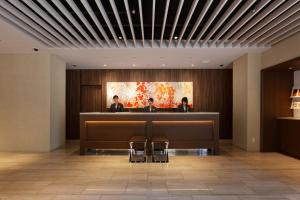 福冈HOTEL FORZA HAKATA-GUCHI的大堂设有接待台,有两人就坐